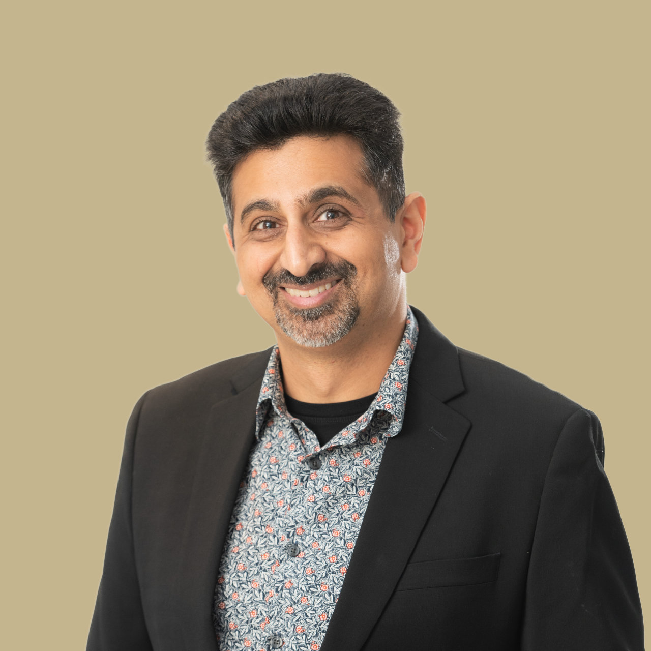 Neel portrait wearing black sports jacket and patterned dress shirt