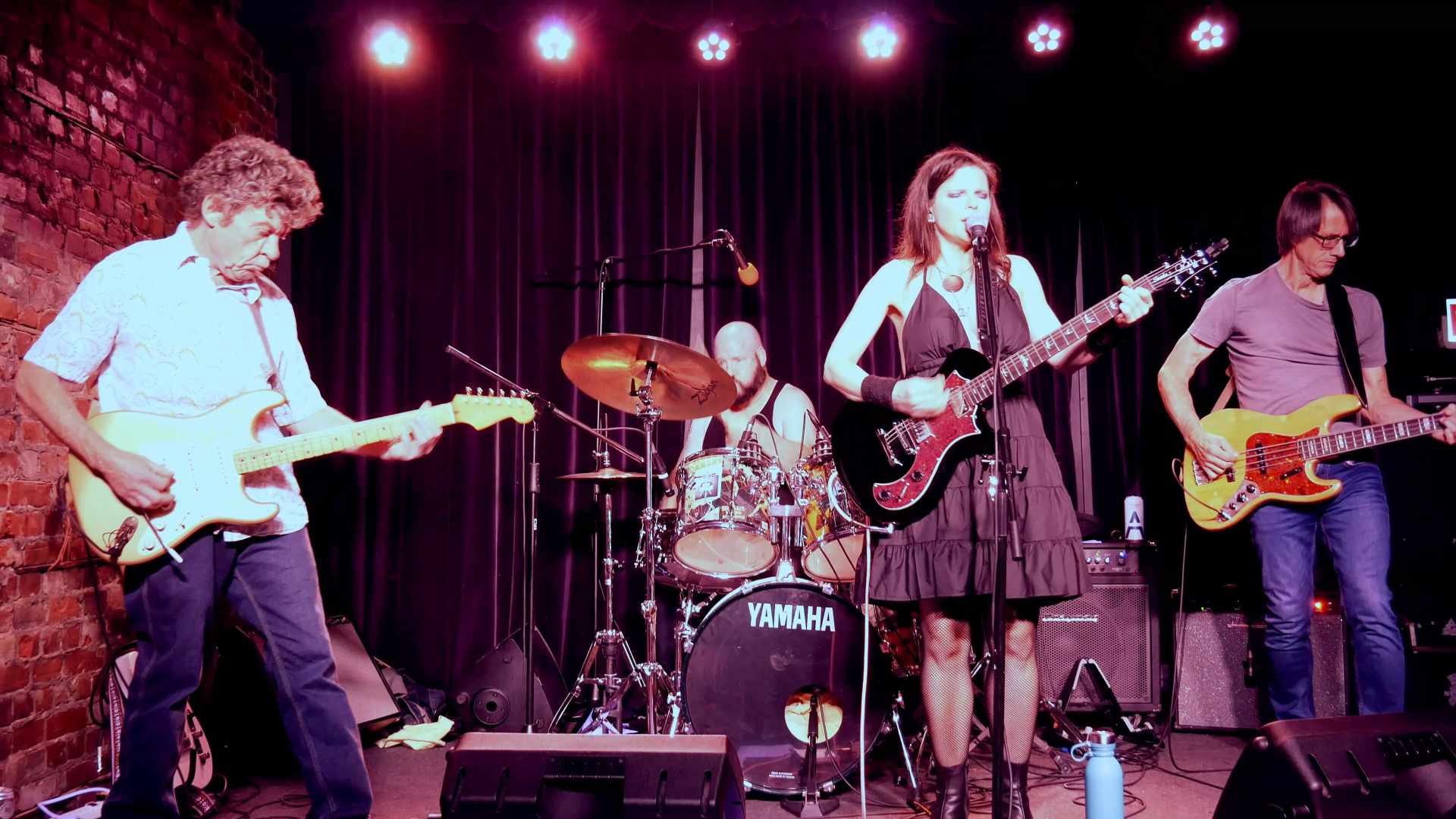 Carmen Toth performing on stage with her band including lead guitar, bass, and drums. At the Cameron House back room in Toronto.